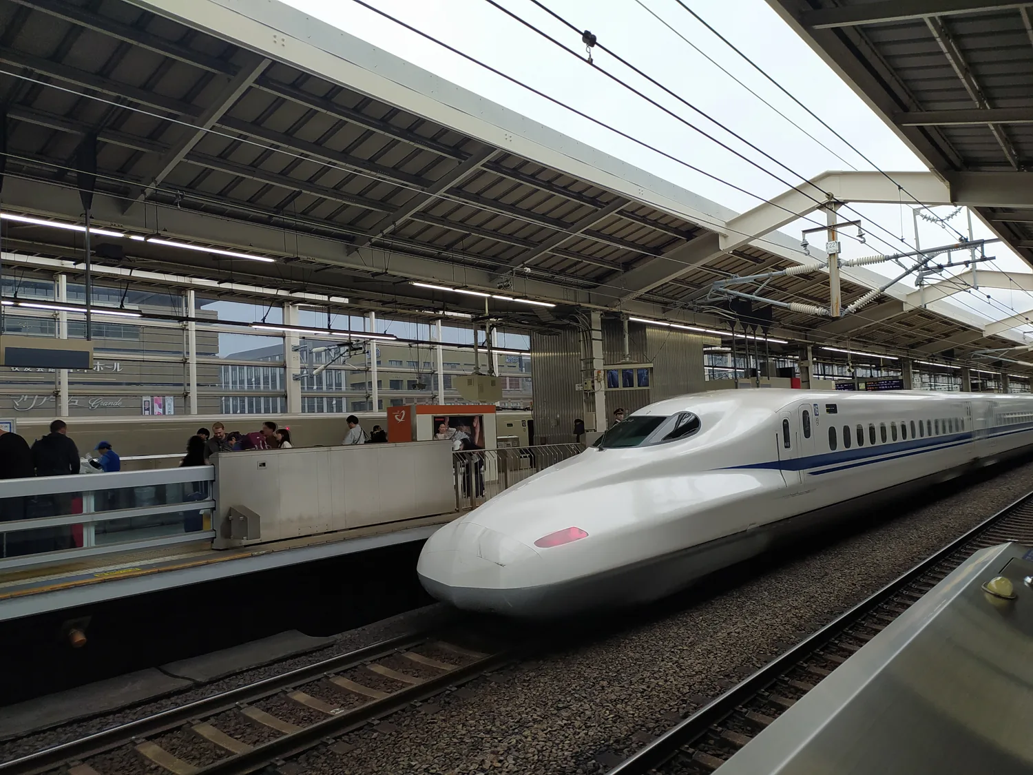 A white N700 Shinkansen bullet train with a blue stripe at Kyoto Station